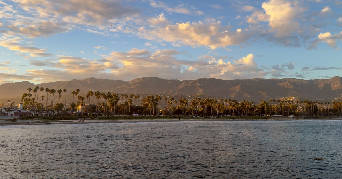 Beautiful coastal view of Santa Barbara with palm trees and mountains during sunset, capturing serene beauty.