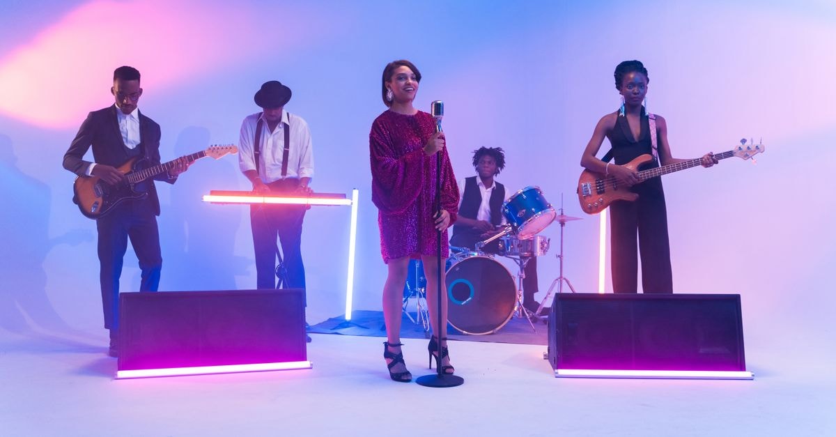 Apple Music and United Record Pressing Unveil ‘This Is Country Music’ Mural in Nashville A vibrant band performing on stage with neon lights and musical instruments, showcasing talent and energy.