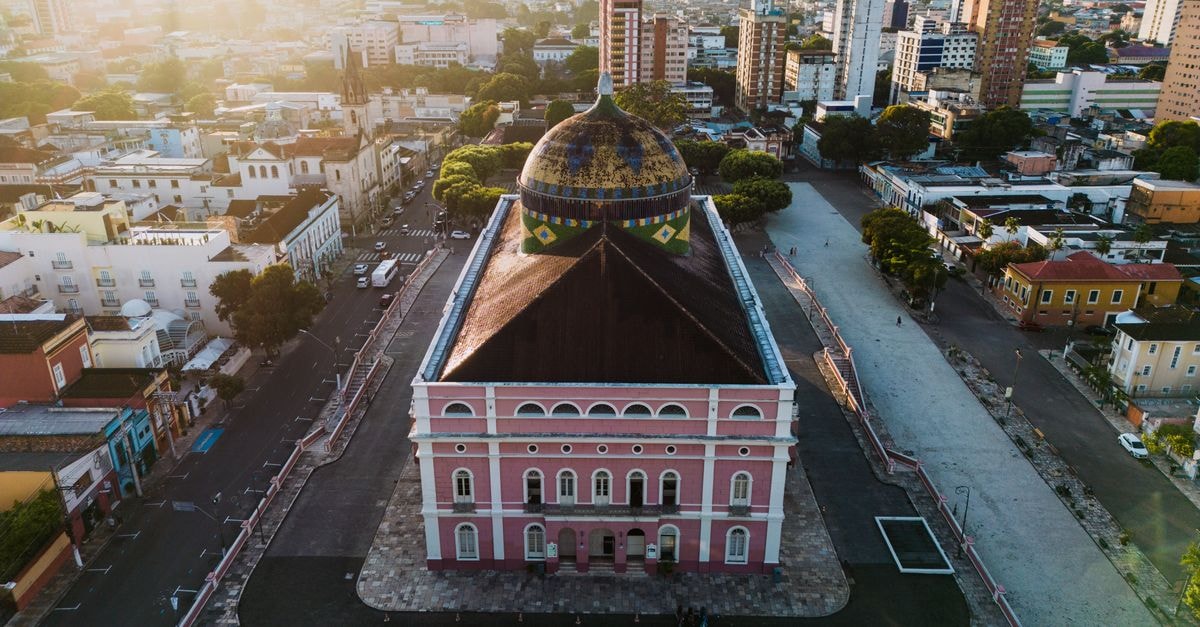 Aerial view of the iconic Teatro Amazonas in Manaus, Brazil, bathed in warm sunset light.