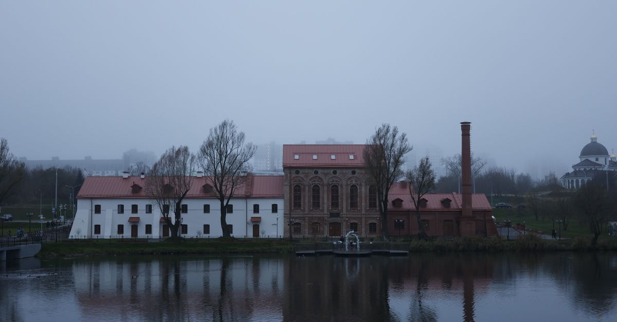 A foggy view of a historic building in Minsk, Belarus with a river reflection.