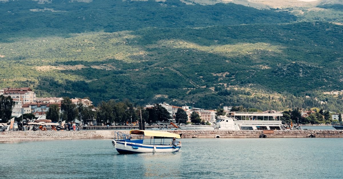 Kozani travel guide: a slow week in West Macedonia Peaceful scene of a boat on Lake Ohrid with a mountainous backdrop in North Macedonia.