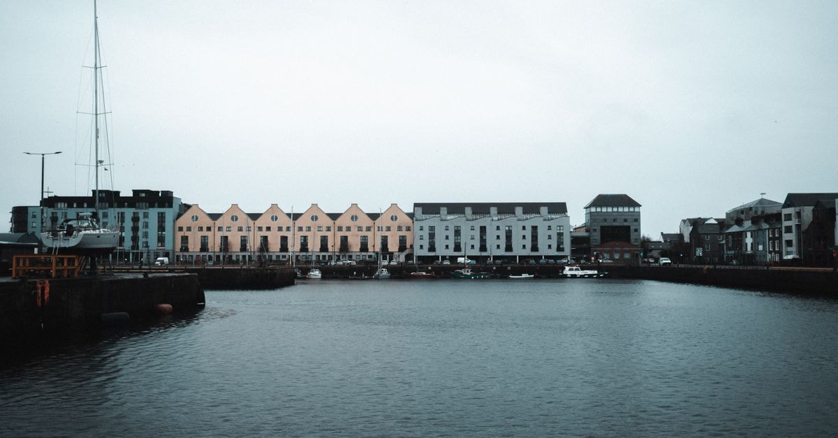 The Skeffington Arms Hotel in Galway: An 1850 Landmark on Eyre Square Scenic view of Galway Harbor with colorful townhouses and boats, showcasing urban waterfront architecture.