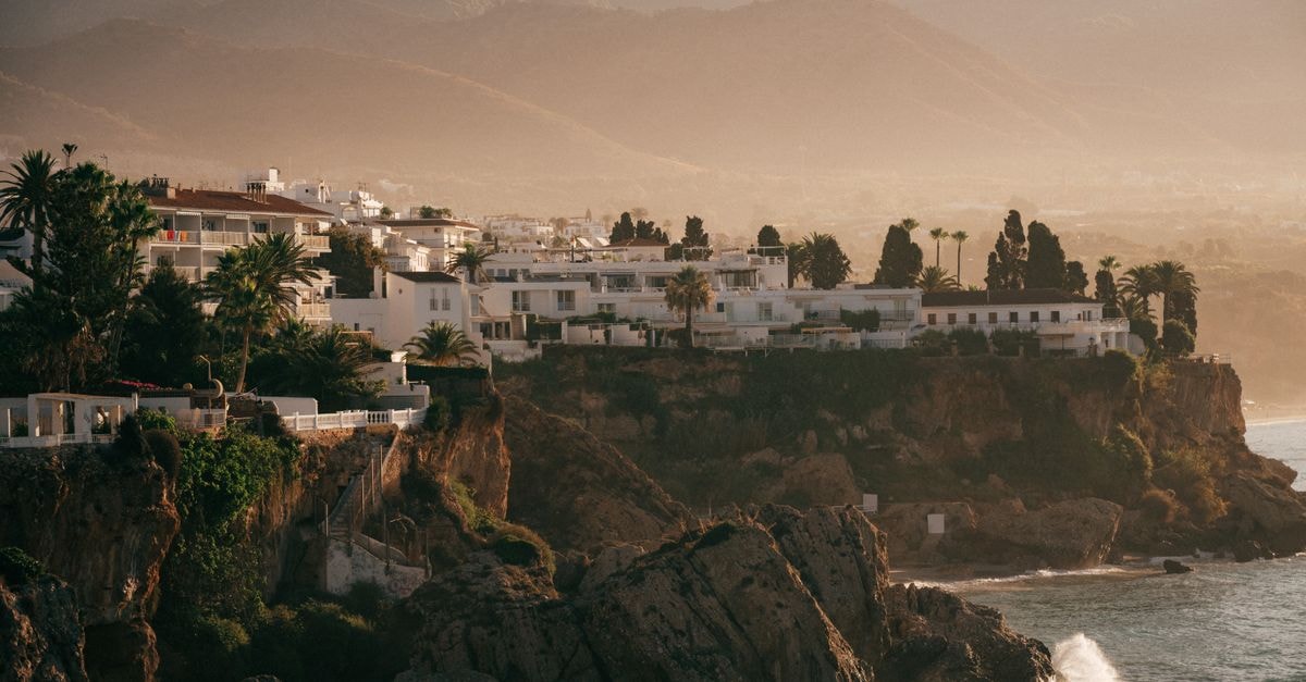 Breathtaking view of a Mediterranean coastal town with cliffs and sunset lighting.