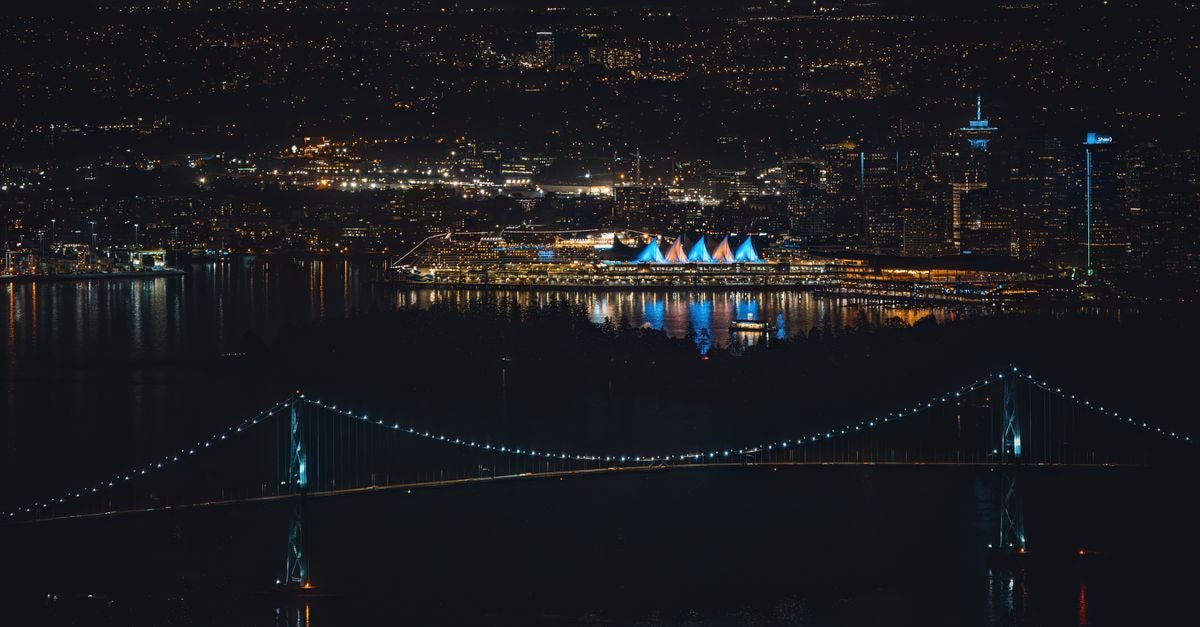Stunning aerial view of Vancouver's illuminated skyline and bridge at night, showcasing vibrant city lights.