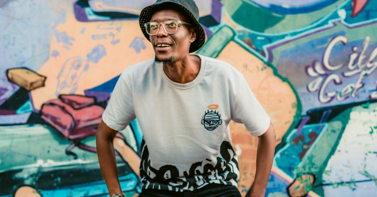 Pretoria Travel Guide: Moving Around and Eating Well Man posing joyfully in front of a vibrant graffiti wall in Pretoria, South Africa.
