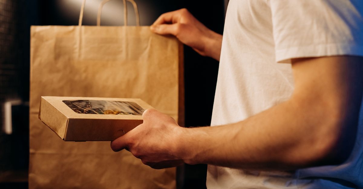 Darling Ingredients: A Cyclical Render-to-Renewables Story at a Scaled but Stretched Price A person presenting a food delivery package and paper bag at home.