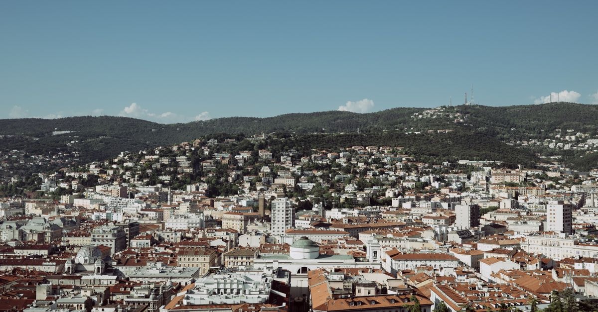 Panoramic view of Trieste's urban sprawl with hilly background on a sunny day.