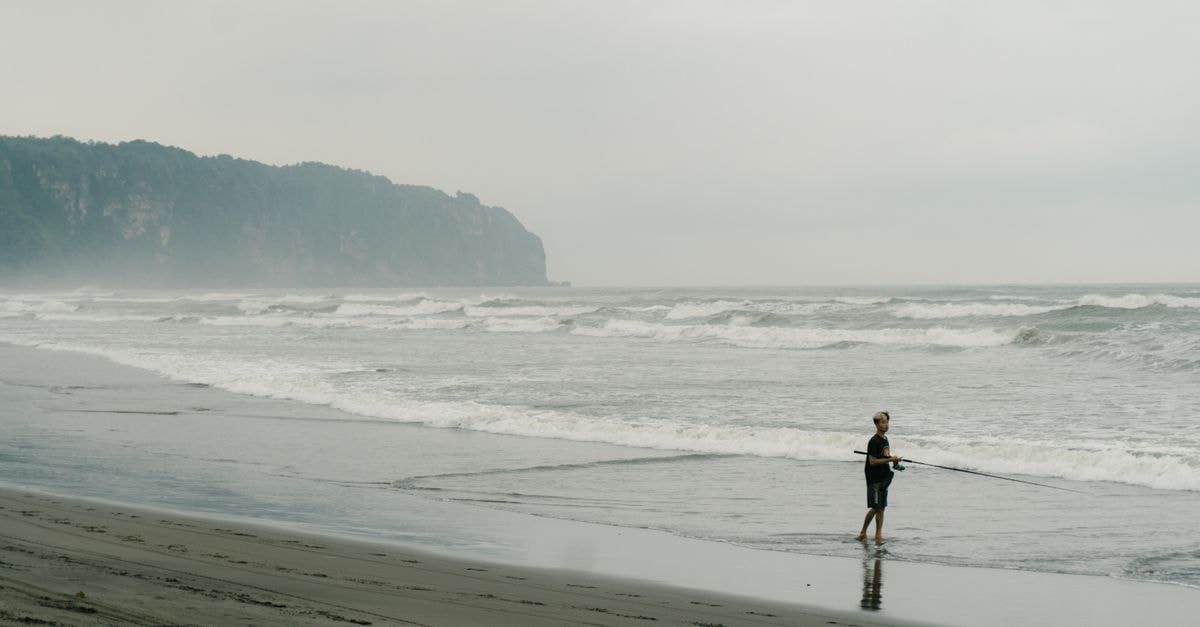 A Quiet Sukabumi Travel Guide: Where Mountains Meet the Sea Man fishing alone on a foggy beach in Kretek, Jogja, Indonesia.