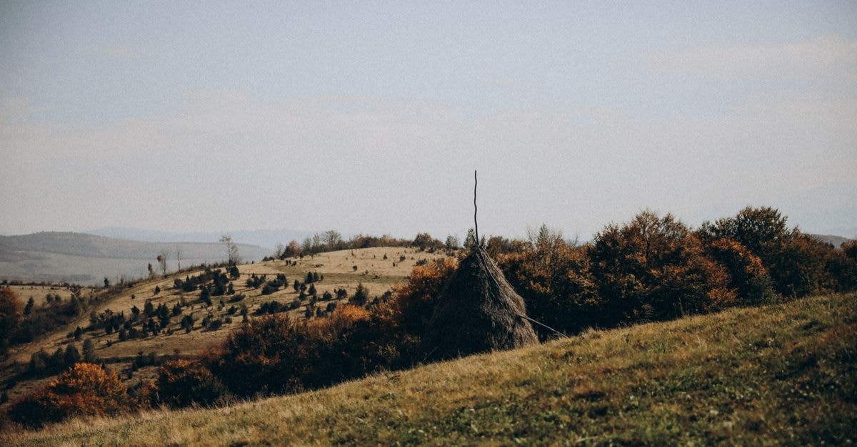 Explore this serene autumn countryside with hills and haystack under a clear sky, perfect for nature lovers.