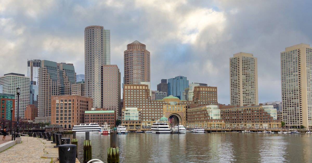 The Langham Boston, Boston — Oliver Street Stay with Indoor Pool and Ballrooms Panoramic view of Boston skyline with modern skyscrapers and harbor reflections, capturing urban architecture.