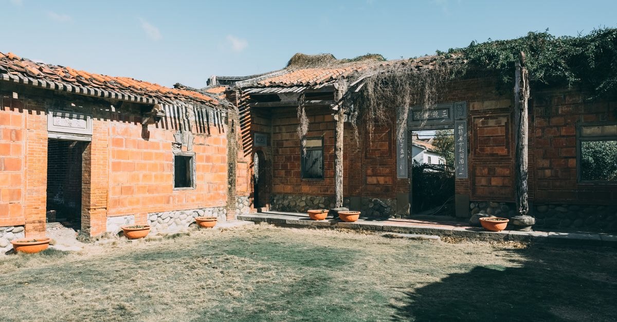A Quiet Yunfu Travel Guide for Slow Guangdong Days Abandoned brick buildings with damaged roofs under a clear blue sky.