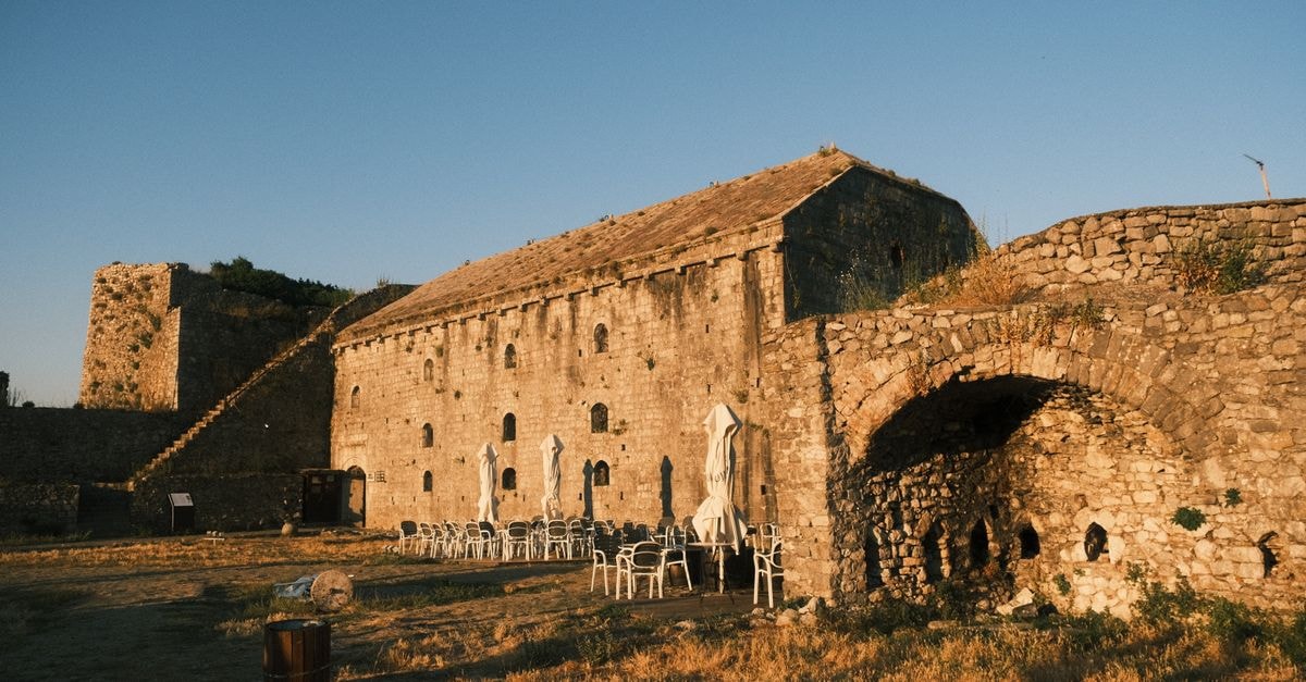 Historic Shkodër Castle in Albania at sunset with empty outdoor seating.