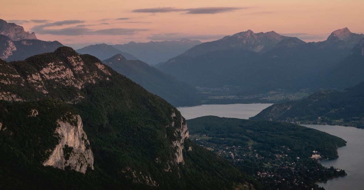 Aparthotel Adagio Annecy Centre: Mountain Air Meets City Stays A breathtaking aerial view of Annecy mountains and lake at sunset, showcasing natural beauty.