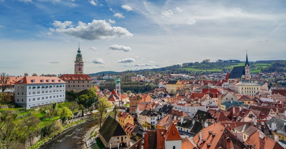 Aerial view of Cesky Krumlov with historic buildings and Vltava River under a blue sky.