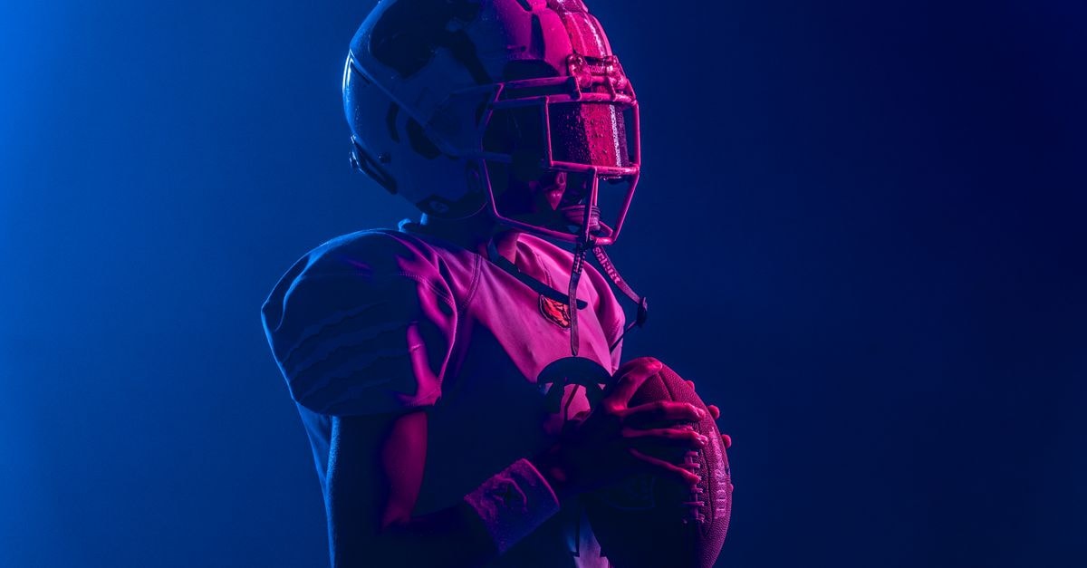 Young athlete in football gear with bold lighting for a dramatic effect.