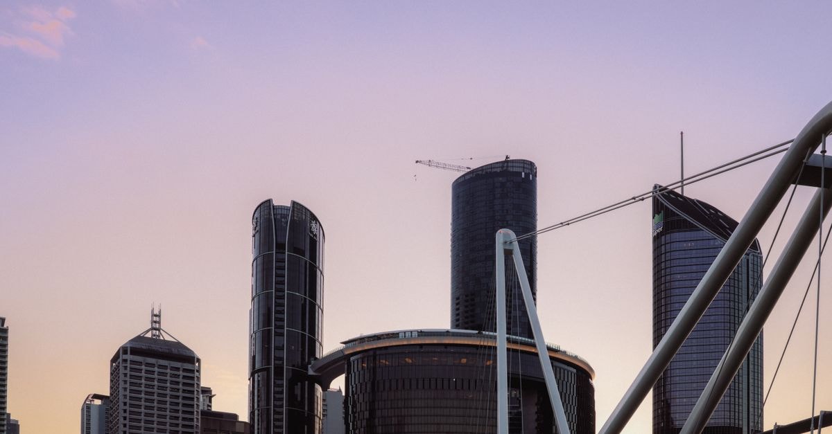 Brisbane travel guide: riverfront ease and foodie finds Captivating view of Brisbane's skyline at sunset, showcasing modern skyscrapers and urban architecture.