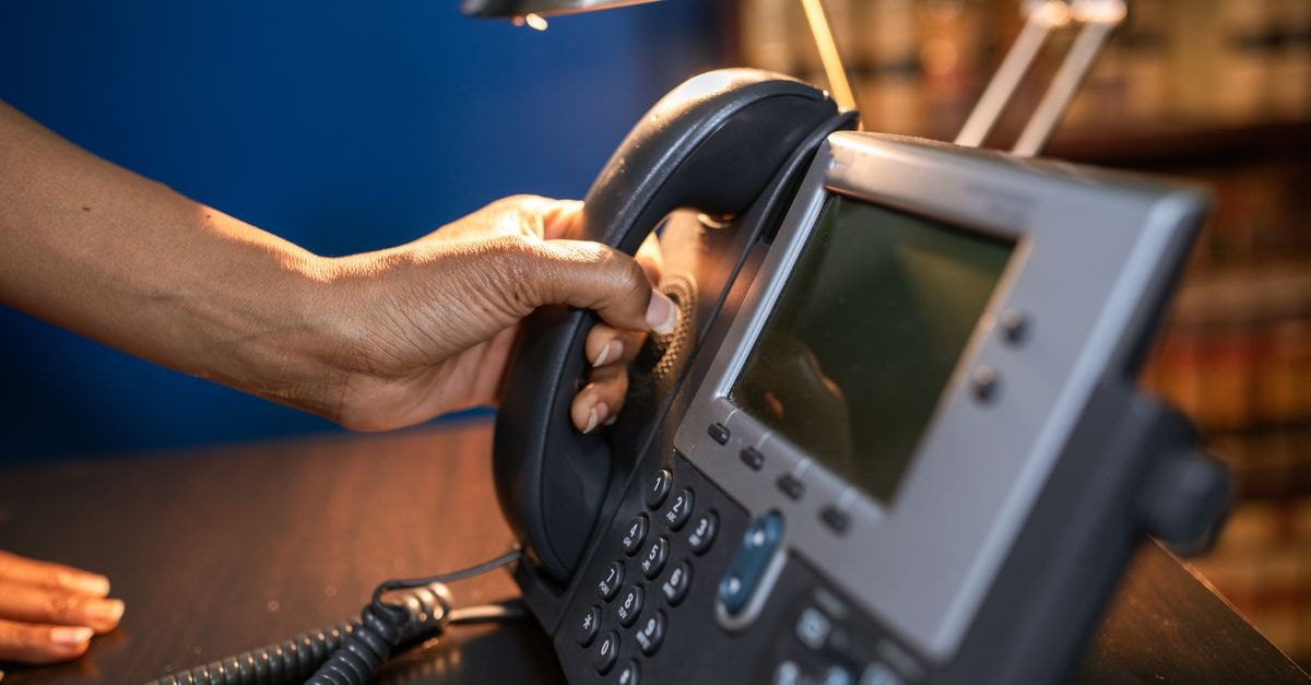 Ciena Corporation: Optical Networking Leader at a Stretched Price A close-up image of a hand picking up a handset from an office telephone, emphasizing communication device usage.