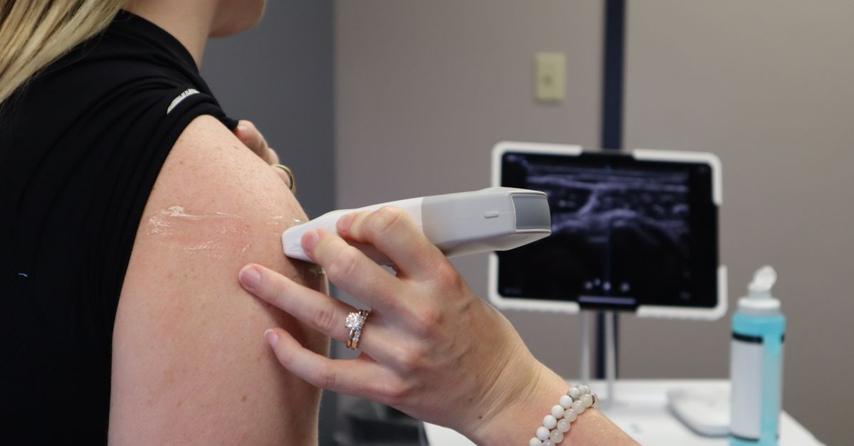 Healthcare professional conducting an ultrasound on a shoulder injury in a medical office.