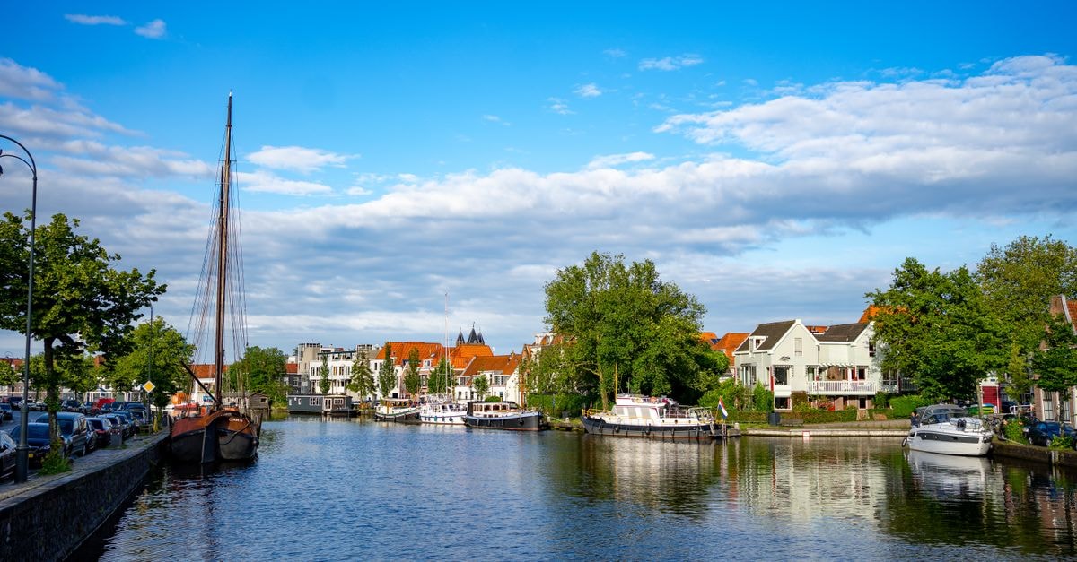 Hotel-Restaurant Middelburg in Middelburg: A Cosy French-Style Retreat by the Zeeland Coast Charming canal in Haarlem, Netherlands, with boats and historic buildings under a vibrant blue sky.