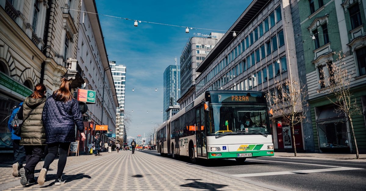A Slow Travel Guide to Tirana: Cafés, Buses, and City Rhythm Street scene in Ljubljana featuring public transportation bus and pedestrians.