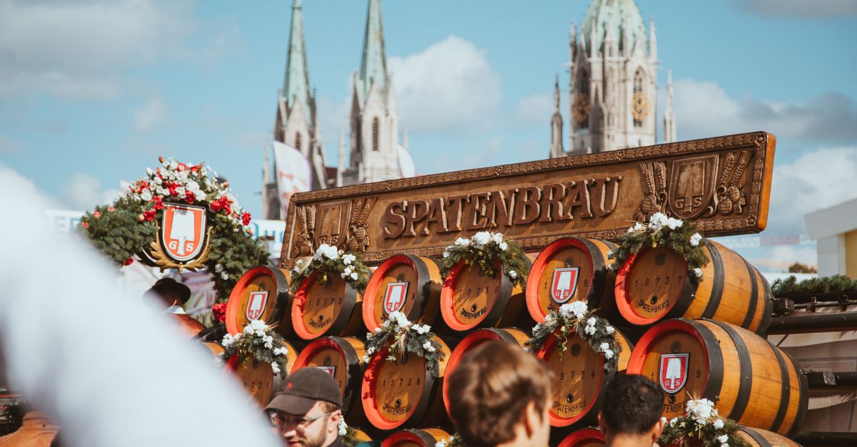 Munich in July 2026: Summer Travel Guide with Beer Gardens, Festivals and Bavarian Food Vibrant Oktoberfest scene at Spatenbräu in München, featuring beer barrels and festival-goers under a clear sky.