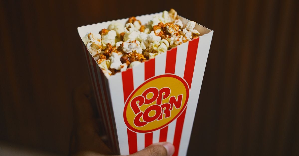Close-up of buttered popcorn in a red-striped box, perfect for movie nights.