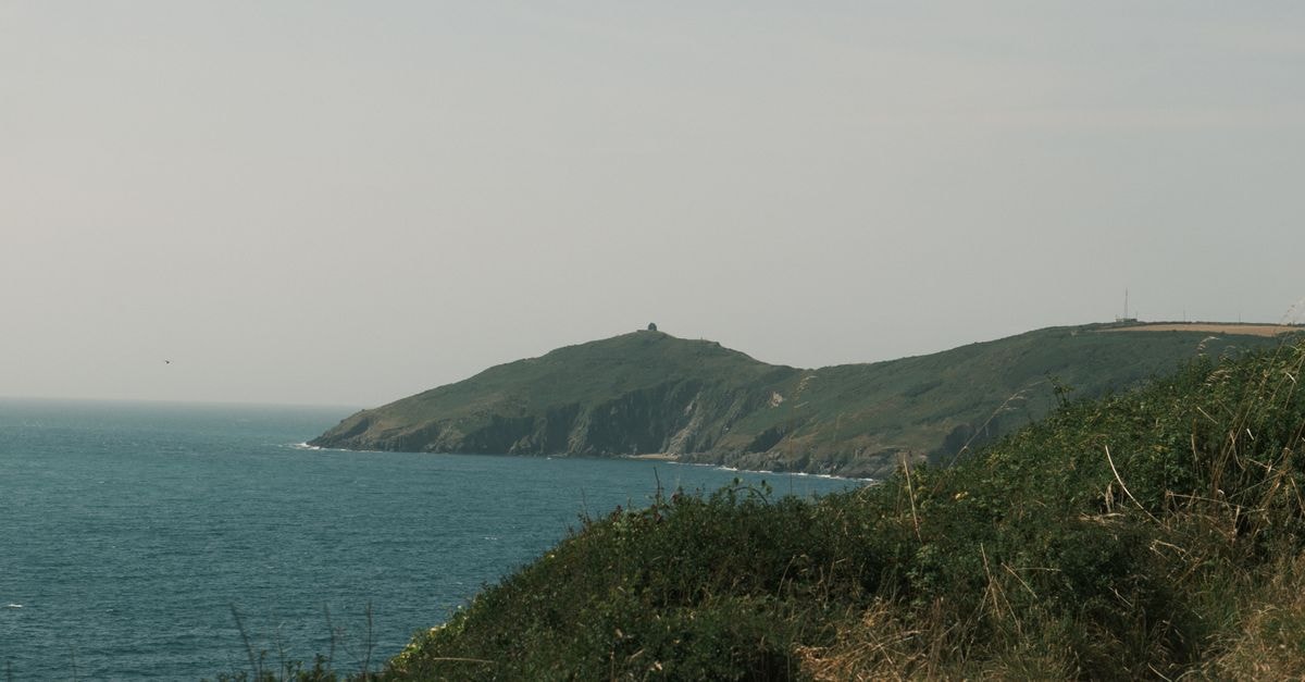 寧靜的海岸風景，懸崖延伸入海，天空柔和。