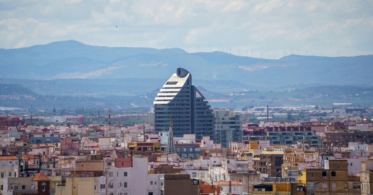 A stunning aerial view of Valencia, Spain featuring the prominent Navis Building against a mountainous backdrop.