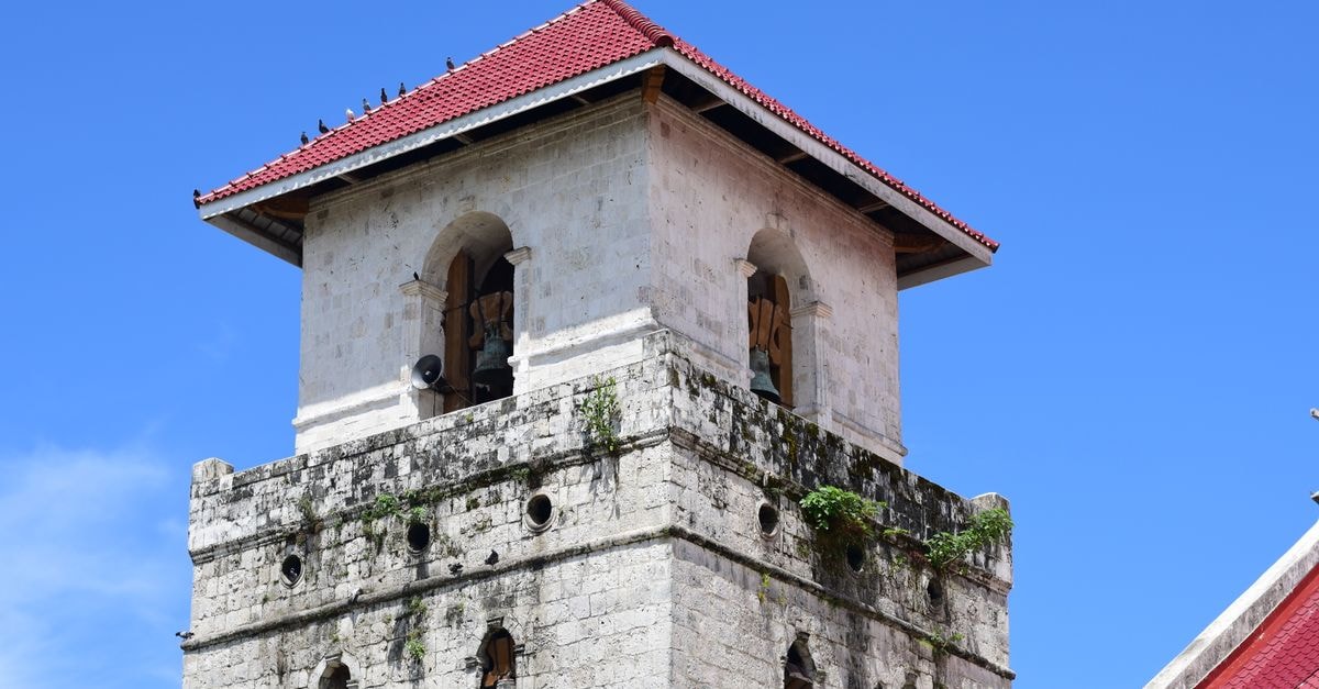 The iconic Baclayon Church bell tower under a clear blue sky, showcasing historical architecture.