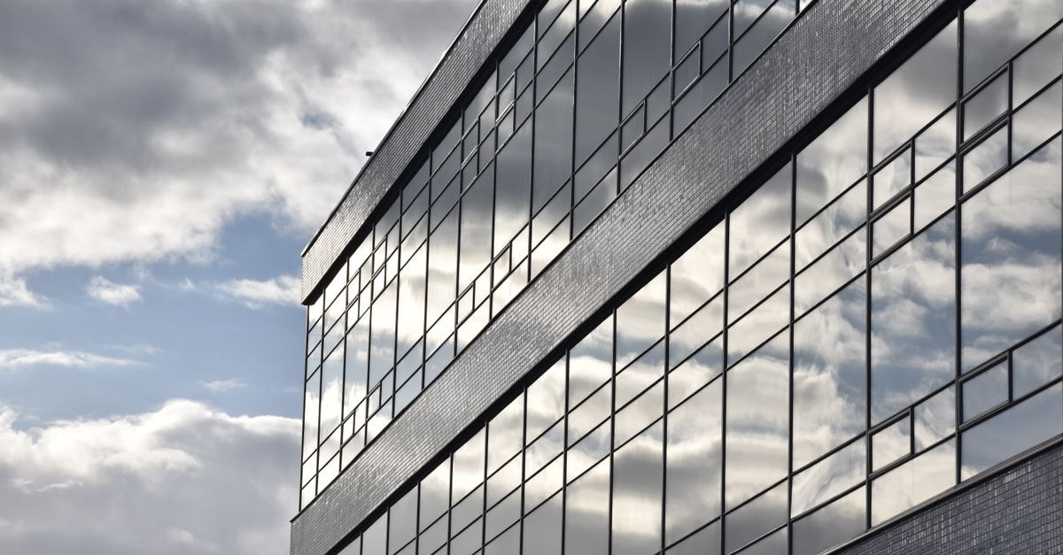 Accenture to acquire Dutch SAP partner McCoy for mid-market push Clouds reflecting on a sleek office building facade in Amsterdam. Urban architecture.