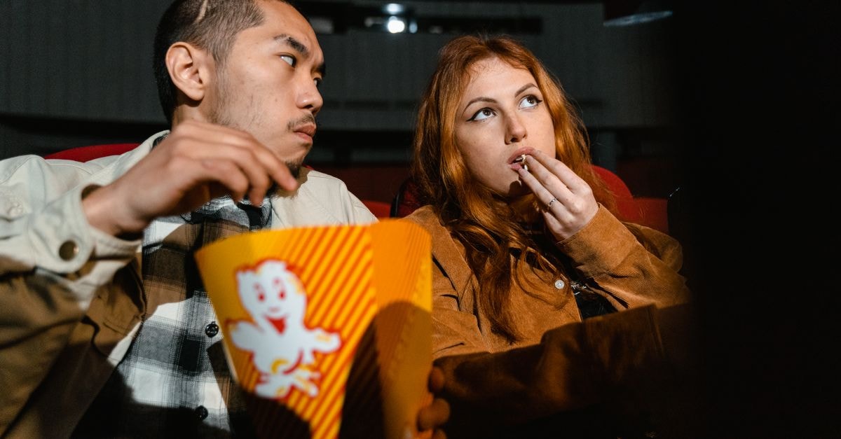 'Spider-Man: Brand New Day' Holds No. 1 in Sixth Weekend, Closes Best Post-Pandemic Summer An Asian man and Caucasian woman enjoying popcorn together in a cozy movie theater.
