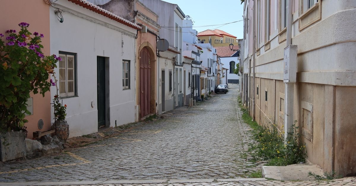 Charming cobblestone street in a historic European town with colorful buildings and flowers.
