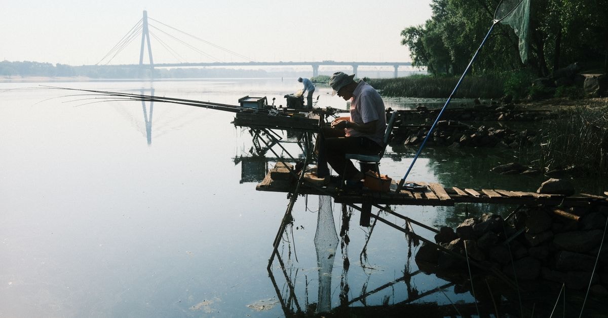 Dnipro Travel Guide: Riverfront Walks and Honest Local Tips Two fishermen enjoy a peaceful morning by the Dnieper River near a bridge in Kyiv.