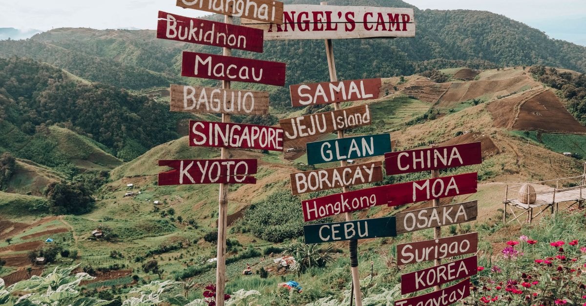Cagayan de Oro Travel Guide: Planning Tips and Things to Do Vibrant signpost with global city names set against Digos City's lush green hills.