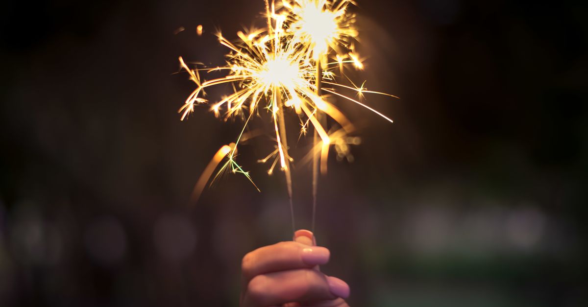 A hand holding sparklers glowing brightly in a dark night, capturing the essence of celebration.