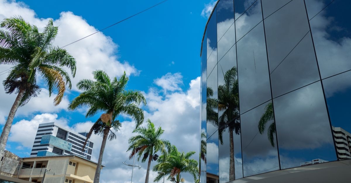 Royal Palm Tower, Campinas — Modern Stay Near Anhanguera Reflective glass building and palm trees under a vibrant blue sky in Campina Grande, Brazil.