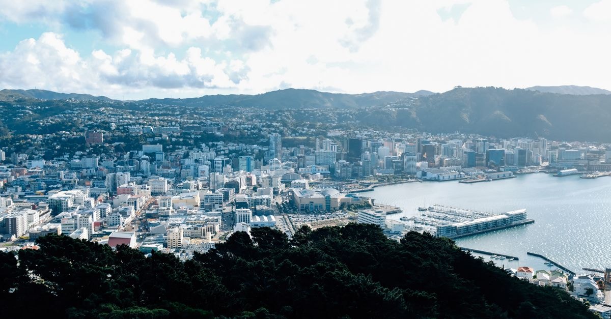 Stunning aerial view of Wellington's urban landscape and waterfront on a sunny day with clouds.