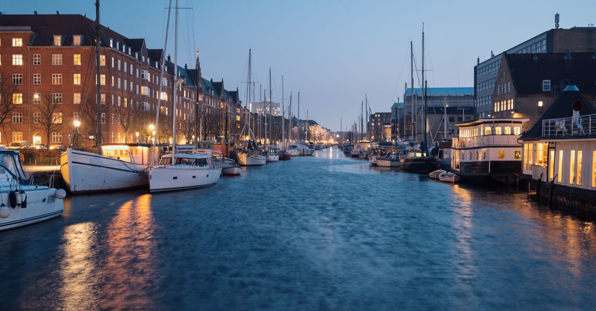 Copenhagen in July 2026: Travel Guide to the Jazz Festival, Harbour Swimming and Peak-Summer Planning Serene night view of illuminated Nyhavn waterfront in Copenhagen with boats and historic buildings.