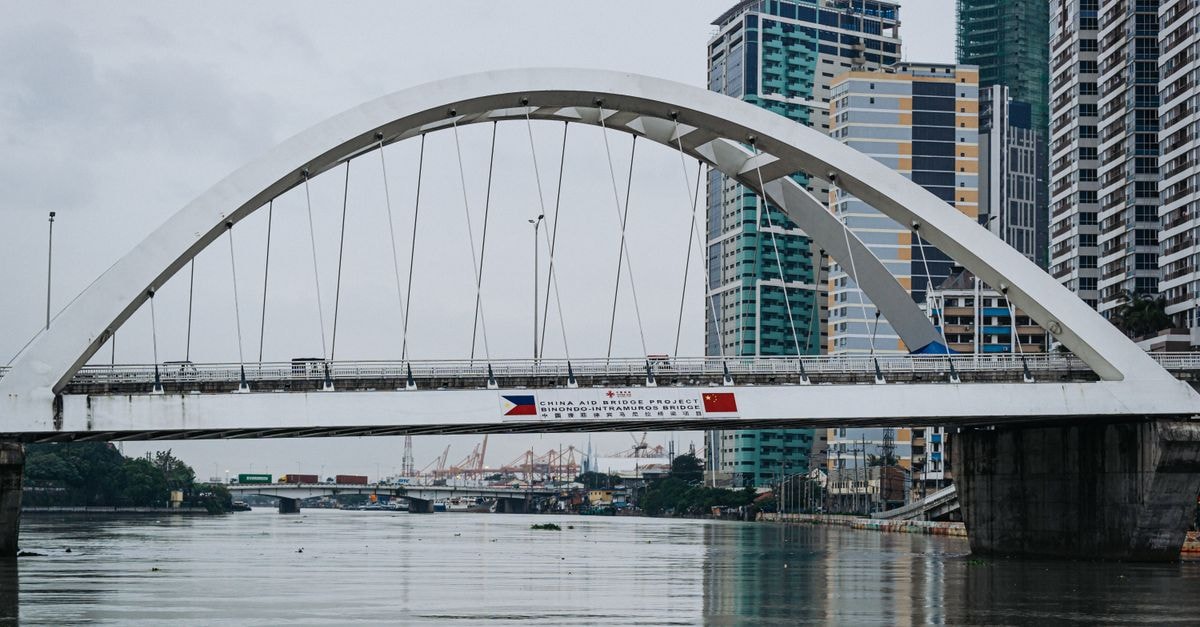 Pearl Blossom Hotel in Manila: A Central Recto Avenue Stay Scenic view of a modern bridge over a river in Manila, with skyscrapers in the background.