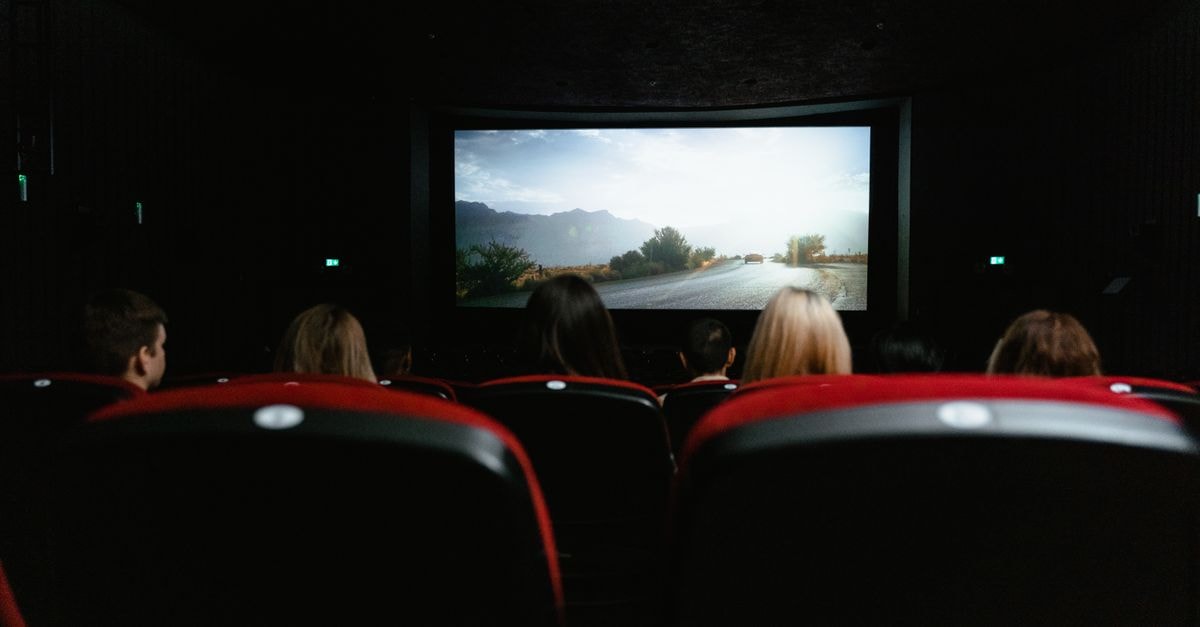Intercontinental Exchange Director Martha Tirinnanzi Sells 1,340 Shares View from behind of people watching a movie in a cinema with red seats and a large screen.