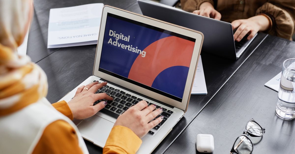 Travelzoo: When Margin Compression Meets Negative Book Value Two professionals work on laptops focusing on digital advertising in an office setting.