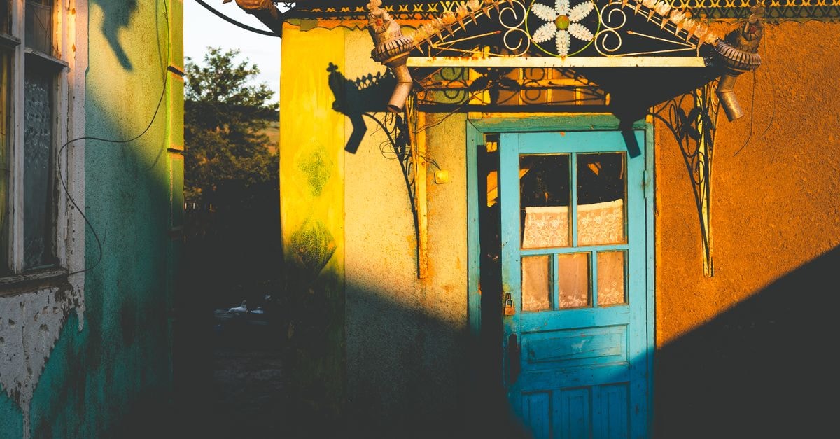 Shymkent Travel Guide: Sunlit Streets of Southern Kazakhstan Vibrant blue door on a rustic house with colorful walls and sunlight casting shadows.