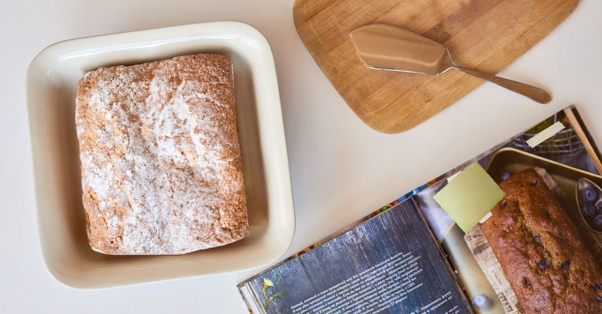 Velenje Travel Guide: Easy Getting Around and a Global Table Freshly baked bread dusted with flour, accompanied by a recipe book and baking tools.