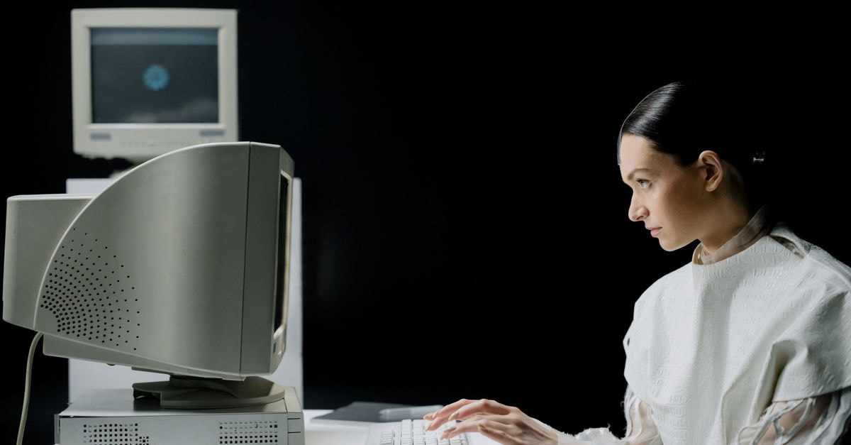 A woman typing on a retro CRT computer in a modern laboratory setting.
