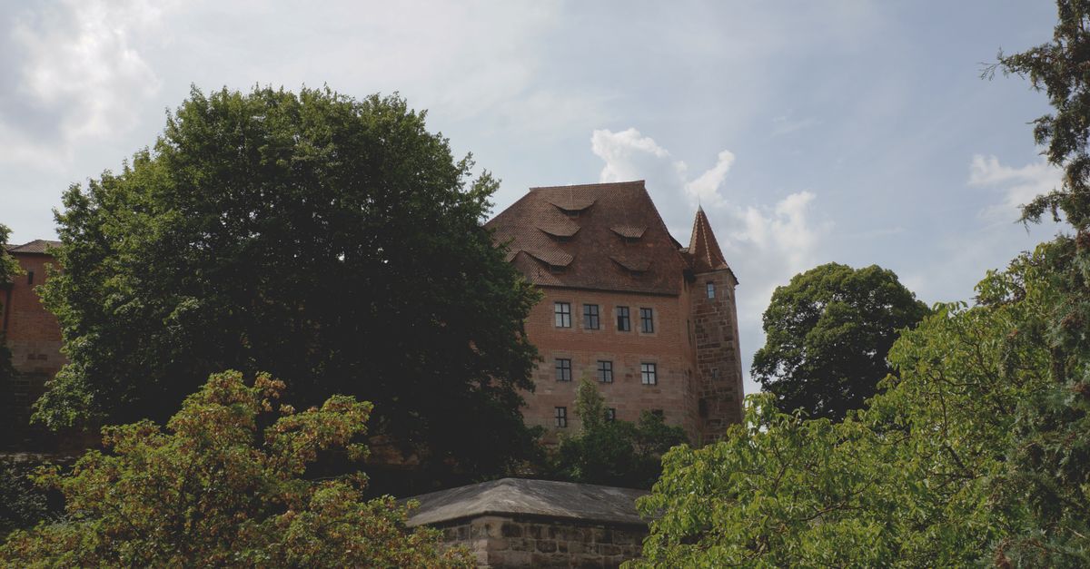 Nuremberg Travel Guide for July 2026: Beer Gardens, the Imperial Castle and Lower Hotel Rates A gothic-style building surrounded by lush greenery in Nürnberg, Germany.