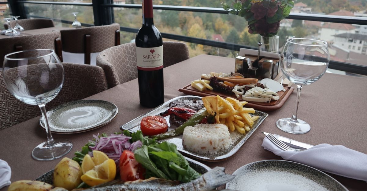 Elegantly set table with wine and gourmet dishes, offering a picturesque view of the landscape.