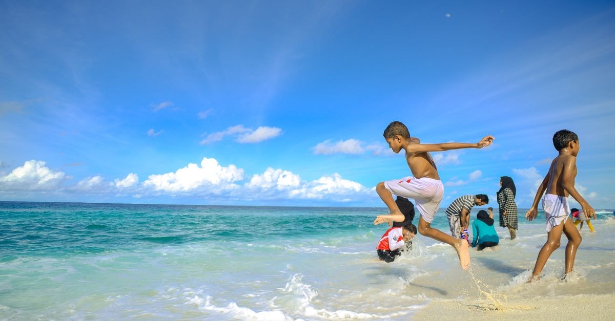 Kavaratti Travel Guide: Island Days and Underwater Wonders Children enjoying the clear waters and sandy beach in the Maldives, capturing a lively summer moment.