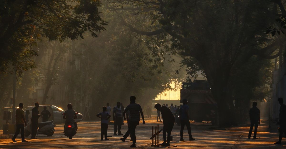 Bhayandar Travel Guide: A Local Pocket of the Mumbai Suburbs Silhouetted people playing cricket on a tree-lined street in Mumbai at dawn.