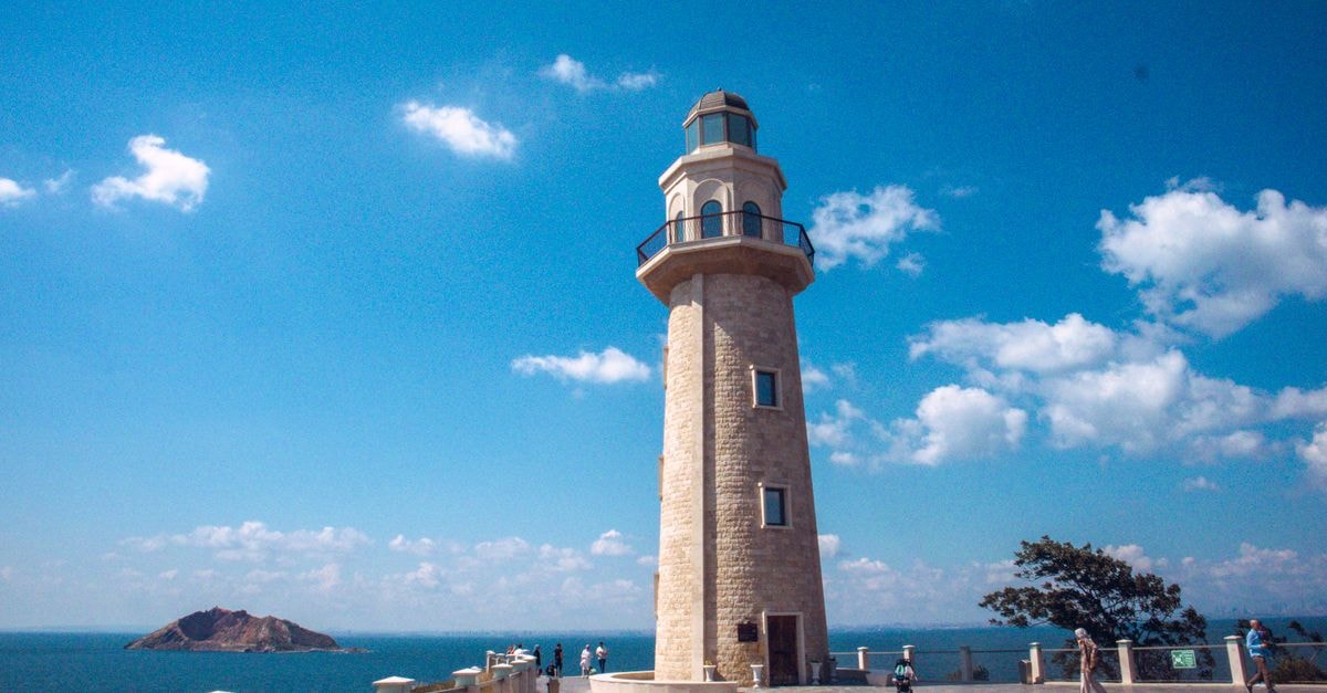 A Quiet Look at Asyut: An Travel Guide Elegant lighthouse on a sunny day with a view of the sea and distant island.