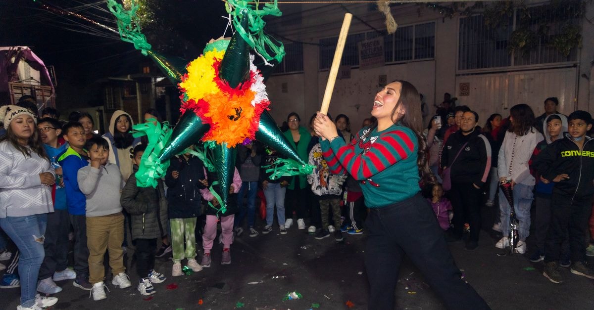 墨西哥市科約阿坎街頭熱鬧的派對，一位女士在歡樂人群中敲打著色彩繽紛的皮納塔。